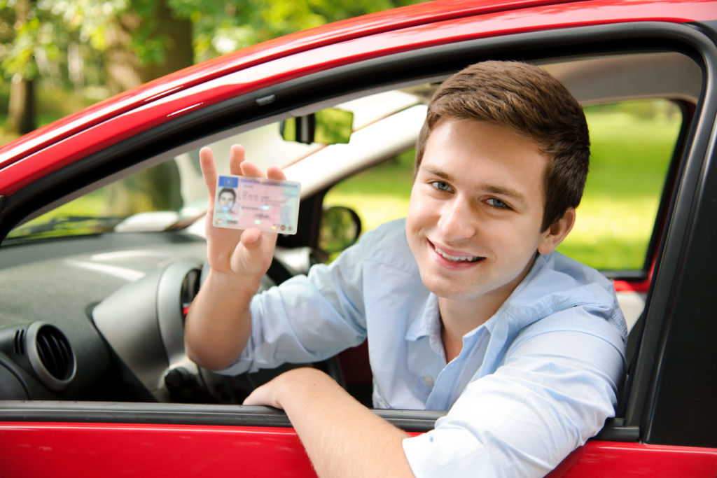 A picture of a teen boy leaning out of a car window showing his driver's license after finishing the Drivers education classes for teens and young adults in Tennesee at Workforce Essentials