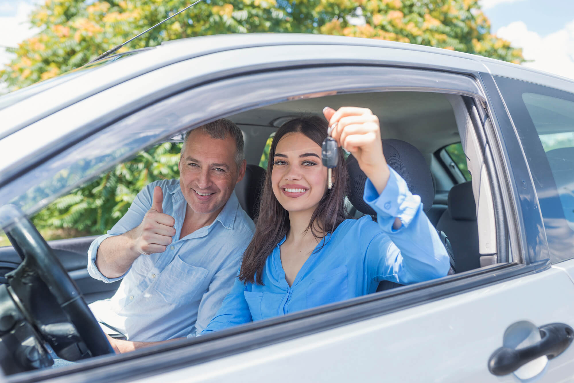 A driver's education instructor and student sitting in a car as the student holds up her keys to show she's ready to start driving. Workforce Essentials offers driver's education classes for adults and minors.
