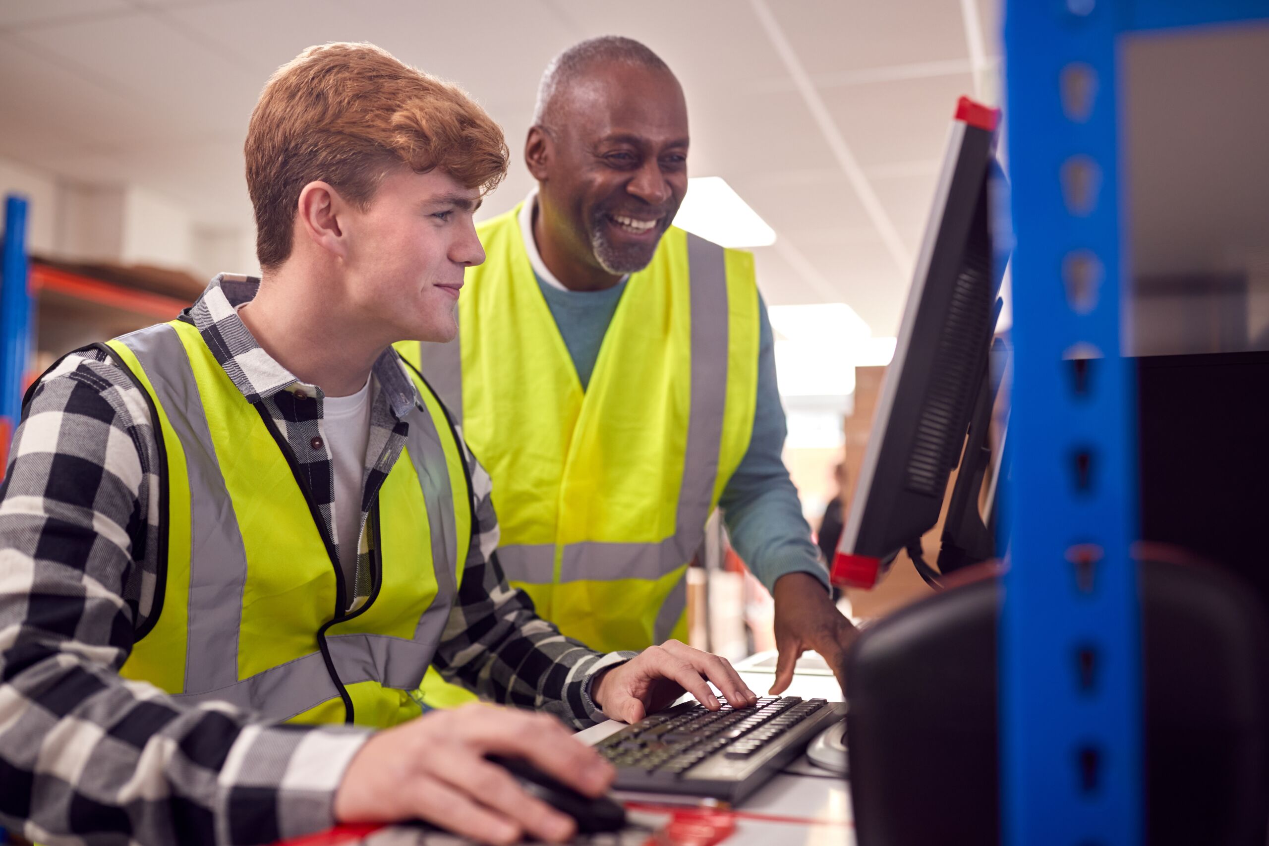 Supervisor helping team member on computer.