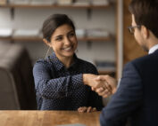 Woman shaking man's hand, smiling.