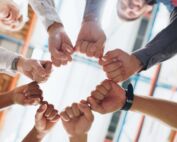 Group of people making a fist bump in a circle at an office