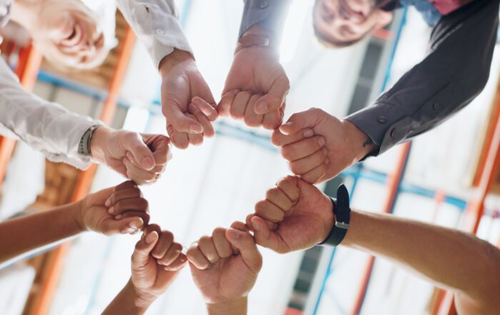 Group of people making a fist bump in a circle at an office