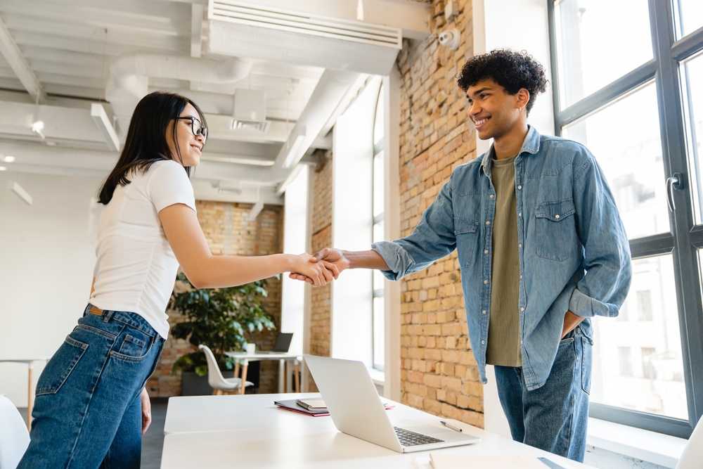 A woman shaking a man's hand over a desk