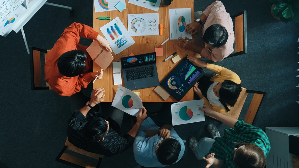 An overhead view of a team working on a project with documents spread out on a table.