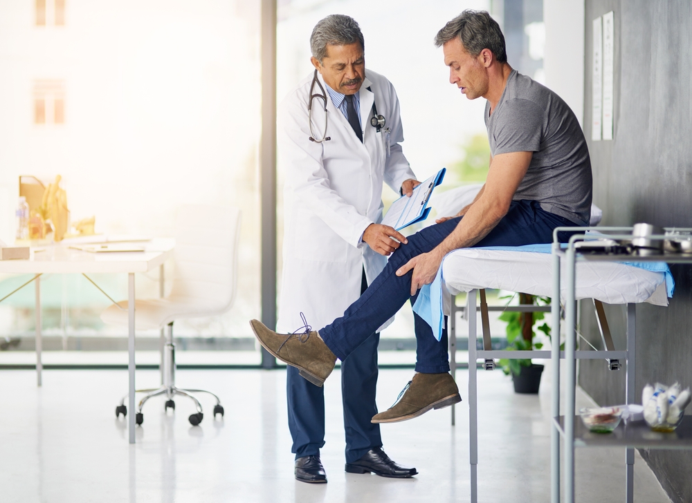 A doctor examining a man's knee.