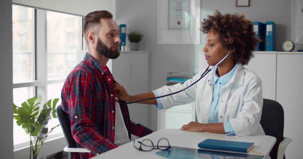 A doctor listening to a man's heart.