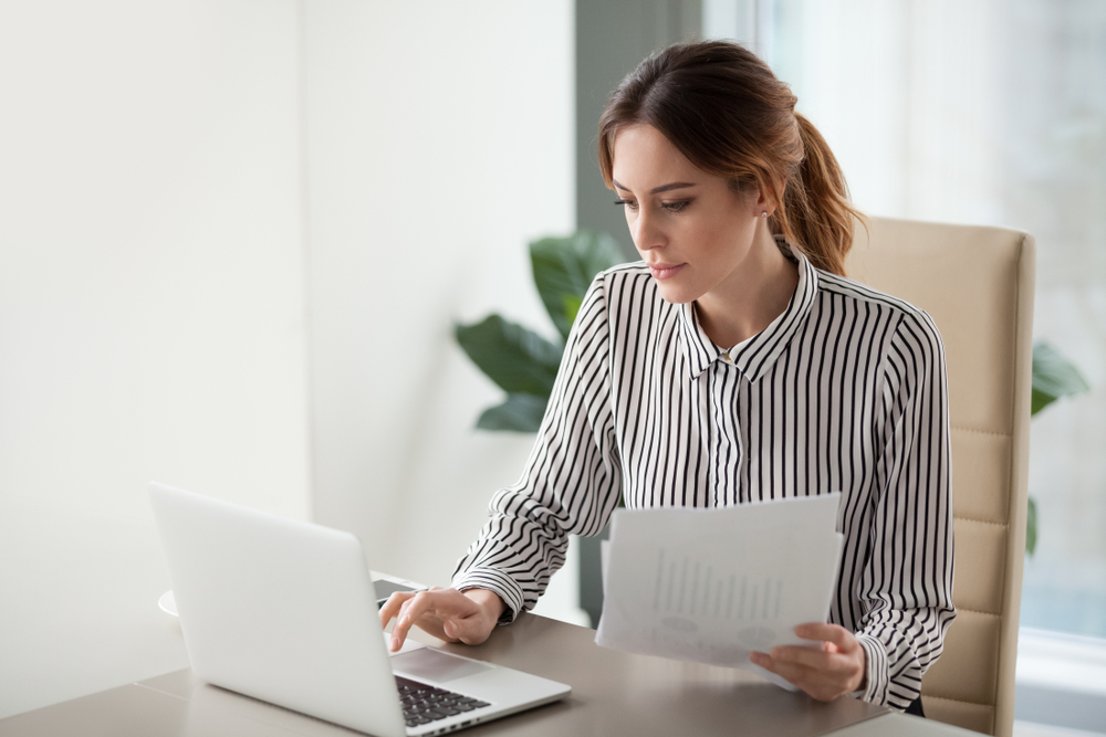 A woman looking over documents at her computer